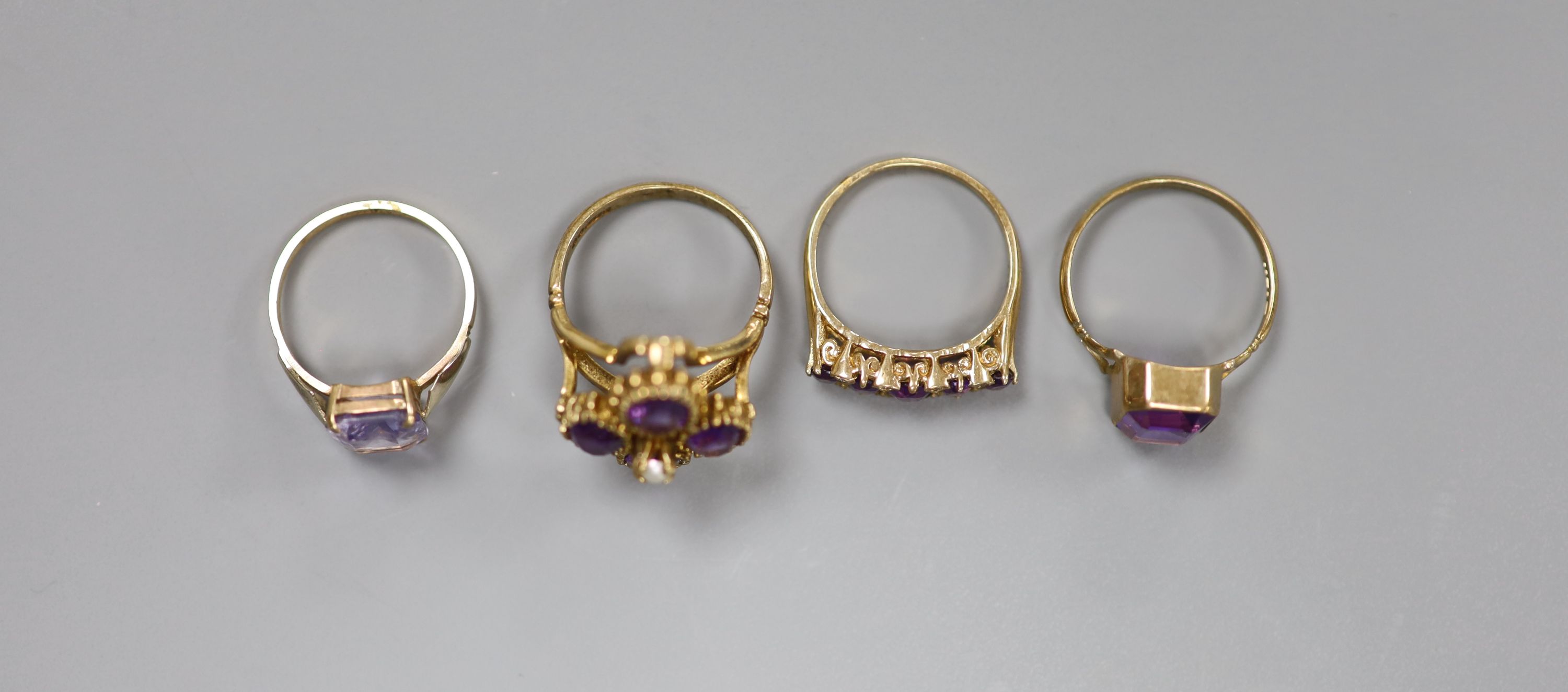 Three assorted 9ct and amethyst set dress rings, including amethyst and diamond and amethyst and seed pearl and one 9ct and amethyst paste ring.